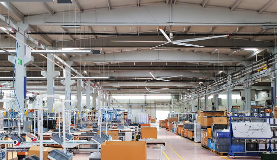 A manufacturing floor with an industrial fan on the ceiling.