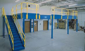 Blue mezzanine with yellow railings over a office doors in a warehouse.