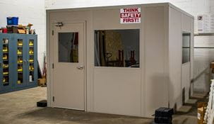 Tan modular office beside tool and parts cabinets in warehouse.