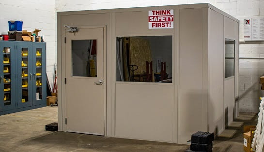 Tan modular office beside tool and parts cabinets in warehouse.