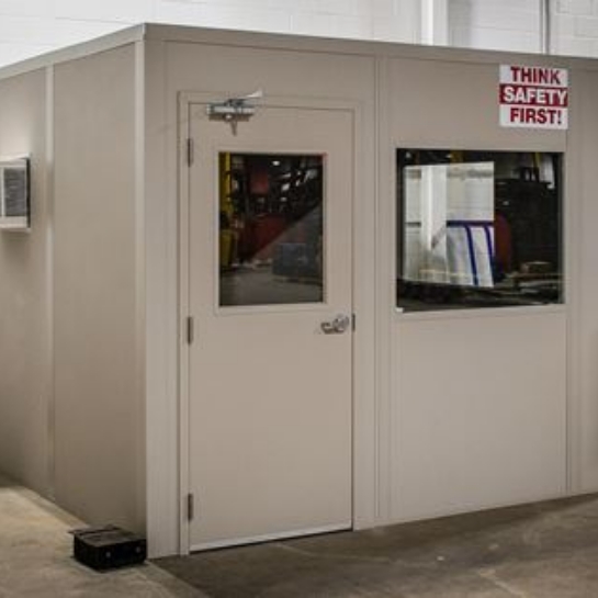 Tan modular office in the back of a warehouse.