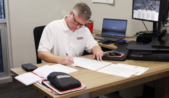 RSC employee reviewing paperwork in Cincinnati branch office. He's surrounded by his computer, monitors and notebooks.