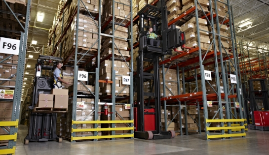 Two orderpickers with operators pulling boxes off racking shelves in a warehouse.