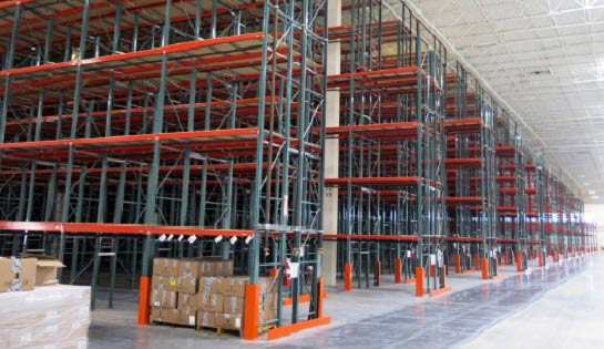 Several aisles of green and red pallet rack in a warehouse.