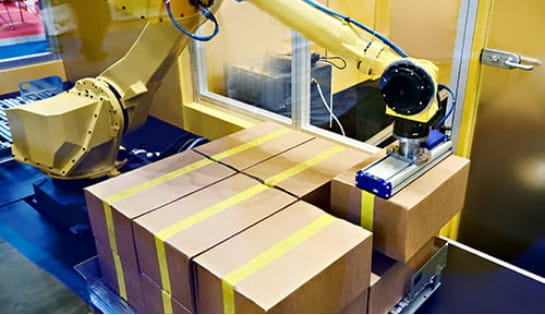 Yellow palletizing robotic arm placing boxes onto pallet.