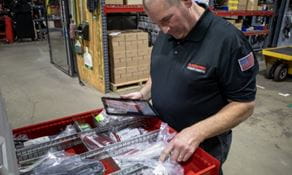 RSCI parts specialist counting inventory for a parts consignment customer in a warehouse. He's holding a tablet.