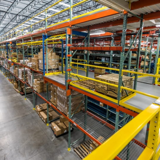 Close up view of a multi-level pick module. Cartons are on different levels with platforms and stairs for workers.