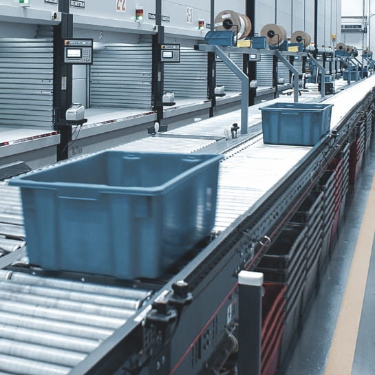 Totes rolling down a conveyor for a picker. In front of multiple VLM systems.