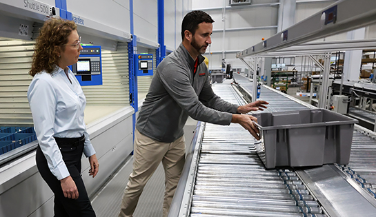 RSC automation specialist demonstrating how a tote picking automation system works to a female customer.