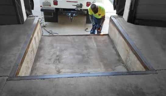 Warehouse dock pit with pit mounted leveler