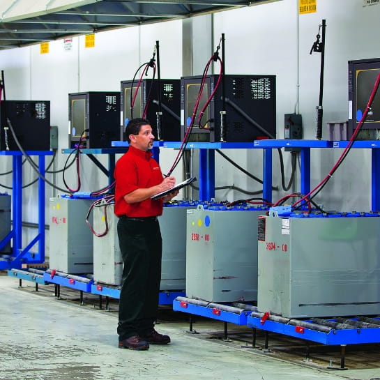 RSC energy specialist with a clipboard reviewing a line of power systems on a warehouse wall.