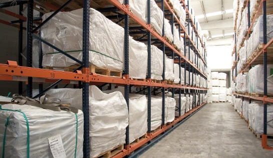 Rack aisle of push back racking holding pallets of wrapped cartons.