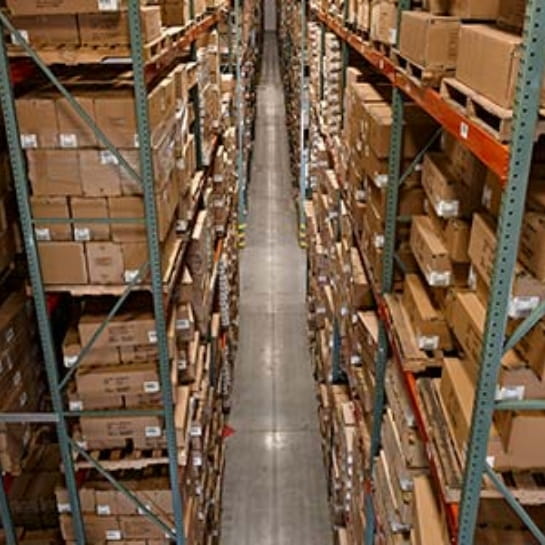 Overhead view of warehouse aisle with green and red racking on either side. Racking full of pallets with boxes.