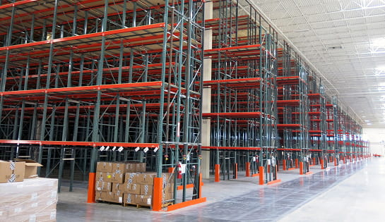 Angled view of several rows of newly installed pallet rack aisles in a Central Ohio retailer warehouse.