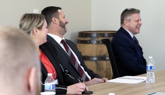 Three RSC employees in professional attire talking and laughing in conference room.