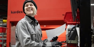 RSC warehouse employee smiling and reviewing a parts order with a Kardex Remstar vertical lift module in the background.