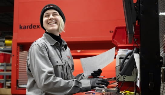 RSC warehouse employee smiling and reviewing a parts order with a Kardex Remstar vertical lift module in the background.
