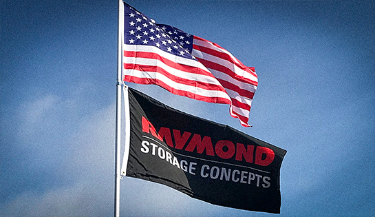 Two flags on a flagpole: American flag on top, and Raymond Storage Concepts flag on bottom. Blue sky in the background.