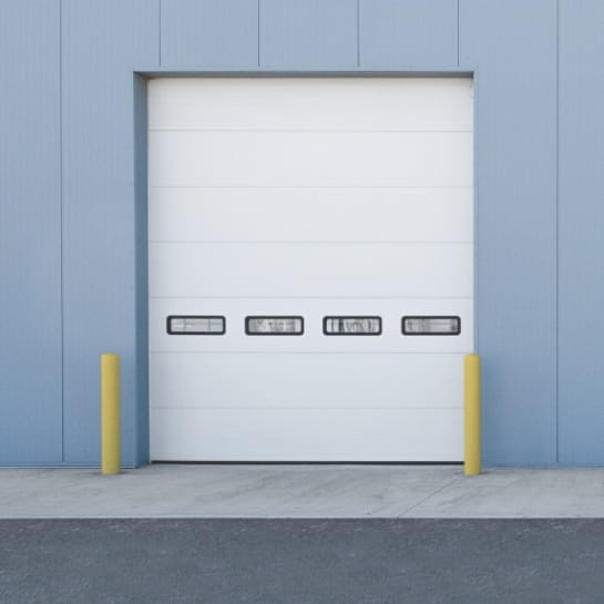 Sectional garage door with four windows on the outside of a warehouse building.