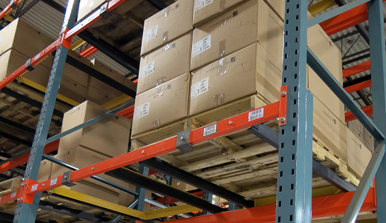 Pallet of cartons sitting on an upper rack of pallet racking system.