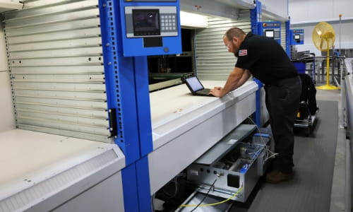 RSCI technician connecting his laptop to AS/RS' mechanical drawer to review software configurations.
