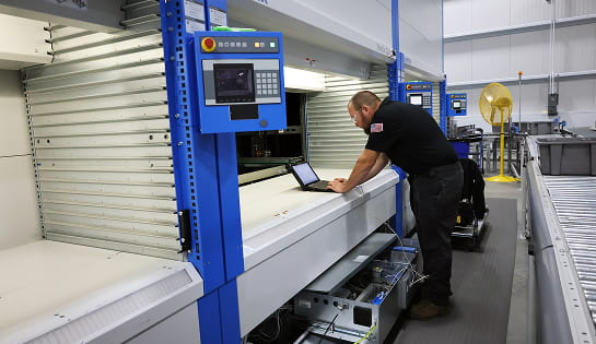 Raymond Storage Concepts technician connecting a laptop to an automated storage and retrieval system mechanical drawer to review software configurations