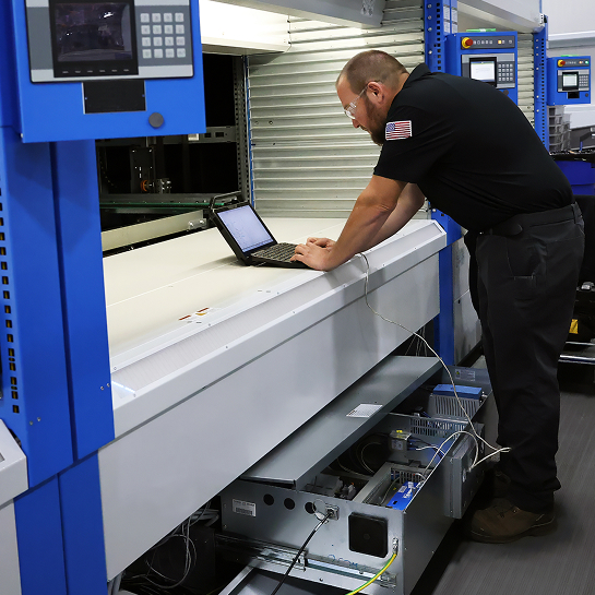 Raymond Storage Concepts technician connecting a laptop to an automated storage and retrieval system mechanical drawer to review software configurations