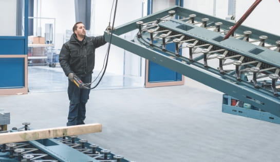 Man holding a crane controller to move a piece of AS/RS.