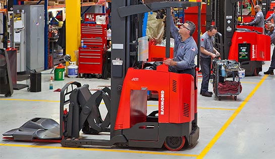Maintenance bay with a couple of technicians working on Raymond forklifts.