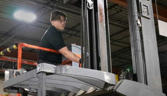 RSC shop technician on a scissor lift is inspecting a forklift's lift for safety and functionality.