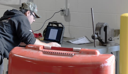 RSC technician is looking at his laptop for diagnostic notes for a nearby forklift during a repair visit.