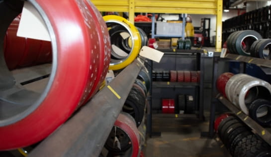 Row of forklift tires lined up on several shelves in a warehouse.
