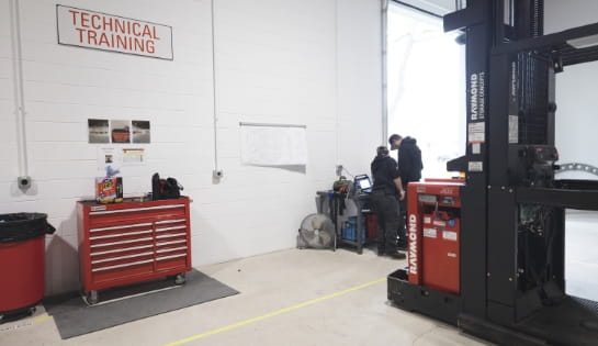 RSC's technician training space in Cincinnati, OH. Two technicians looking at laptops on table next to exposed forklift engine and tool drawer.