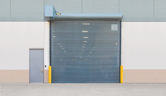 A vented rolling bug garage door preventing pests from coming in on the exterior of a warehouse facility.