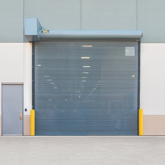 A vented rolling bug garage door preventing pests from coming in on the exterior of a warehouse facility.