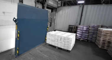 Blue dock leveler in vertically stored position in a warehouse.