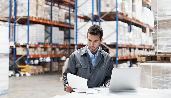 Facility manager reviewing dashboard on computer in distribution center.