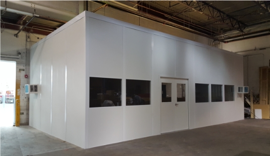 White modular office in a warehouse by an open dock door.