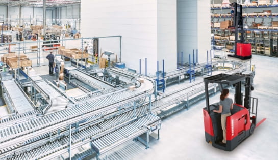 Modern warehouse with automated conveyor, automated storage and retrieval system and racking. Workers sorting through orders in shipping stations. Two Raymond forklifts driving by putting pallets away.