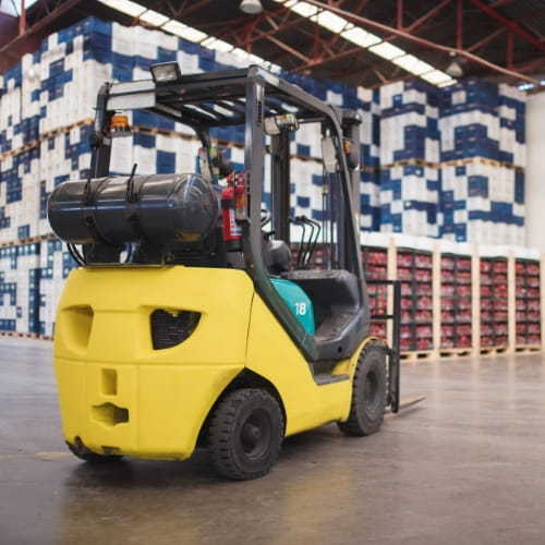 Yellow LP forklift parked in warehouse with racking behind it.